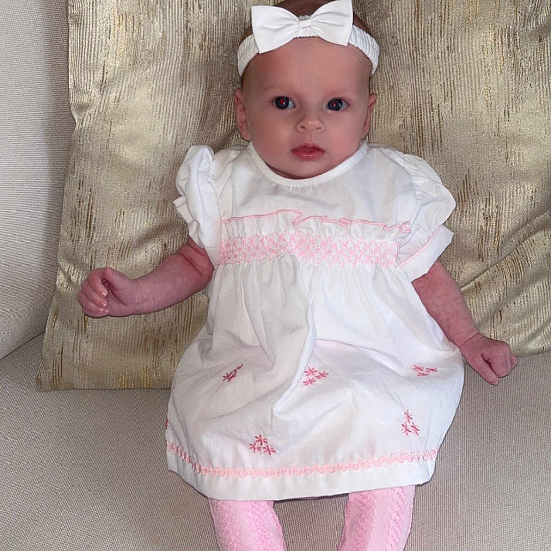 Havanna-Mai joined the competition — help win amazing prizes! baby, beige_couch, bow, child, comfortable, couch, cute, golden_pillow, headband, indoor, infant, pillow, pink_socks, portrait, sitting, small_hands, soft_fabric, texture, white_dress, wide_eyes