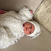 Havanna-Mai joined the competition — help win amazing prizes! baby, infant, knitted_clothing, white_hat, white_blanket, pink_clothing, couch, sofa, cushion, indoors, portrait, cute, small_face, child, cozy, relaxing, warm_clothing, texture, soft, home