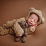 baby, sleeping, costume, bear, plush, knitted_toy, teddy_bear, infant, cute, cozy, brown_background, soft_texture, portrait, child, adorable, newborn, hand, face, closed_eyes, lying_down