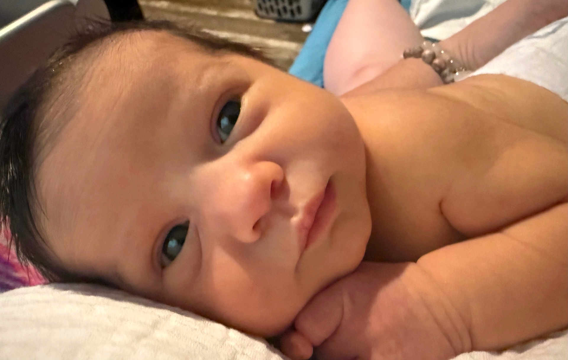 Erica is registered to the contest to win money with this photo: baby, infant, face, skin, hand, lying_down, closeup, newborn, expression, resting, cute, portrait, sleepy, curious, soft_surface, indoors, child, young, human, peaceful