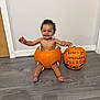 Kobie joined the competition — help win amazing prizes! baby, child, pumpkin, halloween, smiling, floor, wood_floor, wall, door, decoration, holiday, celebration, cute, infant, sitting, happy, orange, costume, festive, indoor
