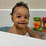 Kobie is registered to the contest to win money with this photo: baby, child, smiling, bath, bathtub, toy, yellow_duck, water, curly_hair, happy, face, skin, indoor, cute, playful, infant, person, toddler, fun, bath_time