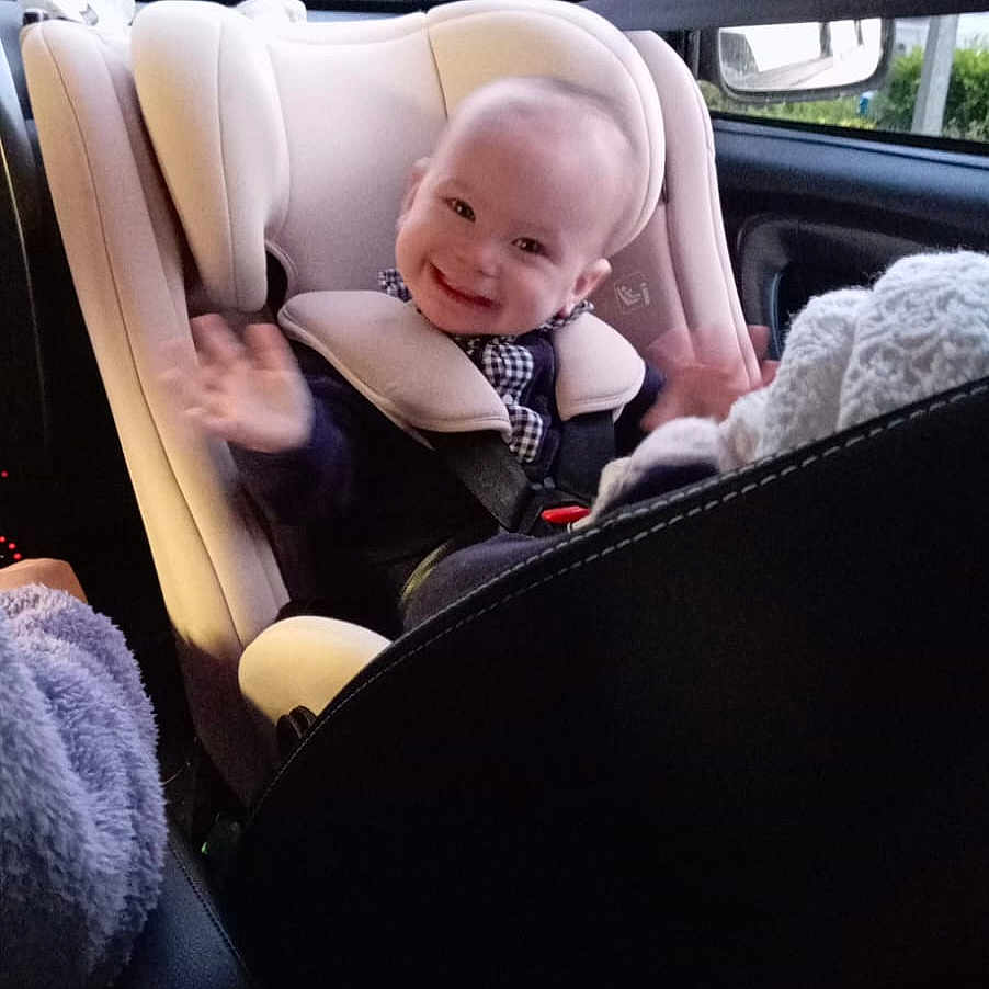 Madeleine a rejoint le concours — aidez-le/la à gagner de superbes lots ! automobile, baby, car_door, car_interior, car_seat, child, child_safety, clothing, face, happy, head, infant, person, seat, seatbelt, smiling, travel, vehicle, waving, window