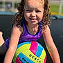 active, beach_volleyball, child, close_up, colorful, curly_hair, fun, girl, happy, outdoor, playful, pony_tails, portrait, purple_clothing, recreation, smiling, sports_equipment, summer, sunlight, young_child