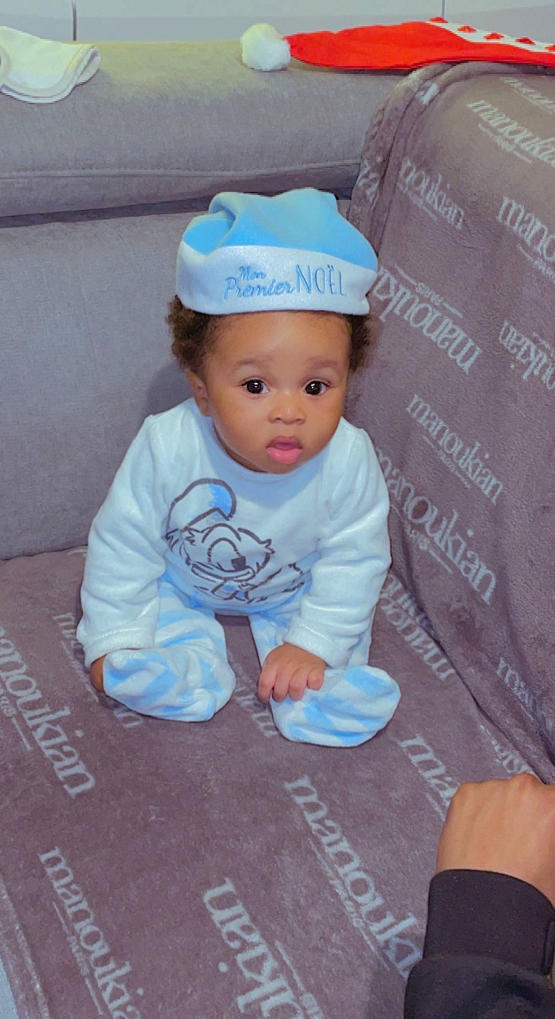 Ezechiel participe au concours pour gagner de l'argent avec cette photo : baby, baby_products, baby_toddler_clothing, beanie, cap, child, concrete, fashion_accessory, flooring, font, hat, hoodie, linens, pattern, person, product, road_surface, sitting, sleeve, surprise