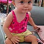toddler, child, indoor, sitting, pink_top, yellow_shorts, curly_hair, glasses, couch, carpet, furniture, book, chair, cute, portrait, young_child, casual, expression, person, home