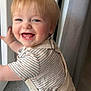 James participe au concours pour gagner de l'argent avec cette photo : toddler, child, smiling, happy, indoor, window, light, overalls, striped_shirt, blonde_hair, face, portrait, cute, baby, person, standing, joy, clothing, skin, expression