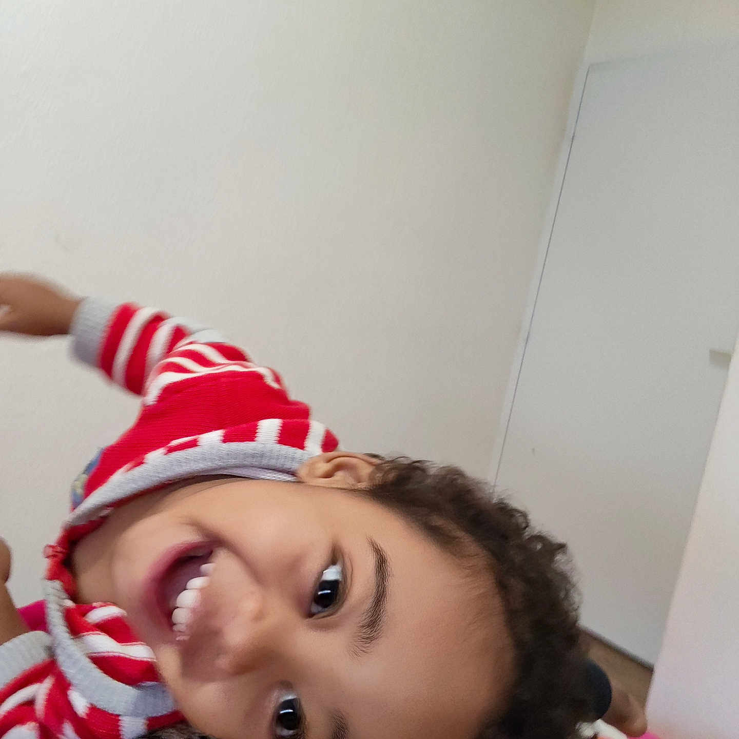 Jahime participe au concours pour gagner de l'argent avec cette photo : bedroom, casual_clothing, child, closeup, curly_hair, expression, eyes, face, happy, head, indoor, joyful, person, playful, portrait, red_sweater, skin, smiling, striped_clothing, young