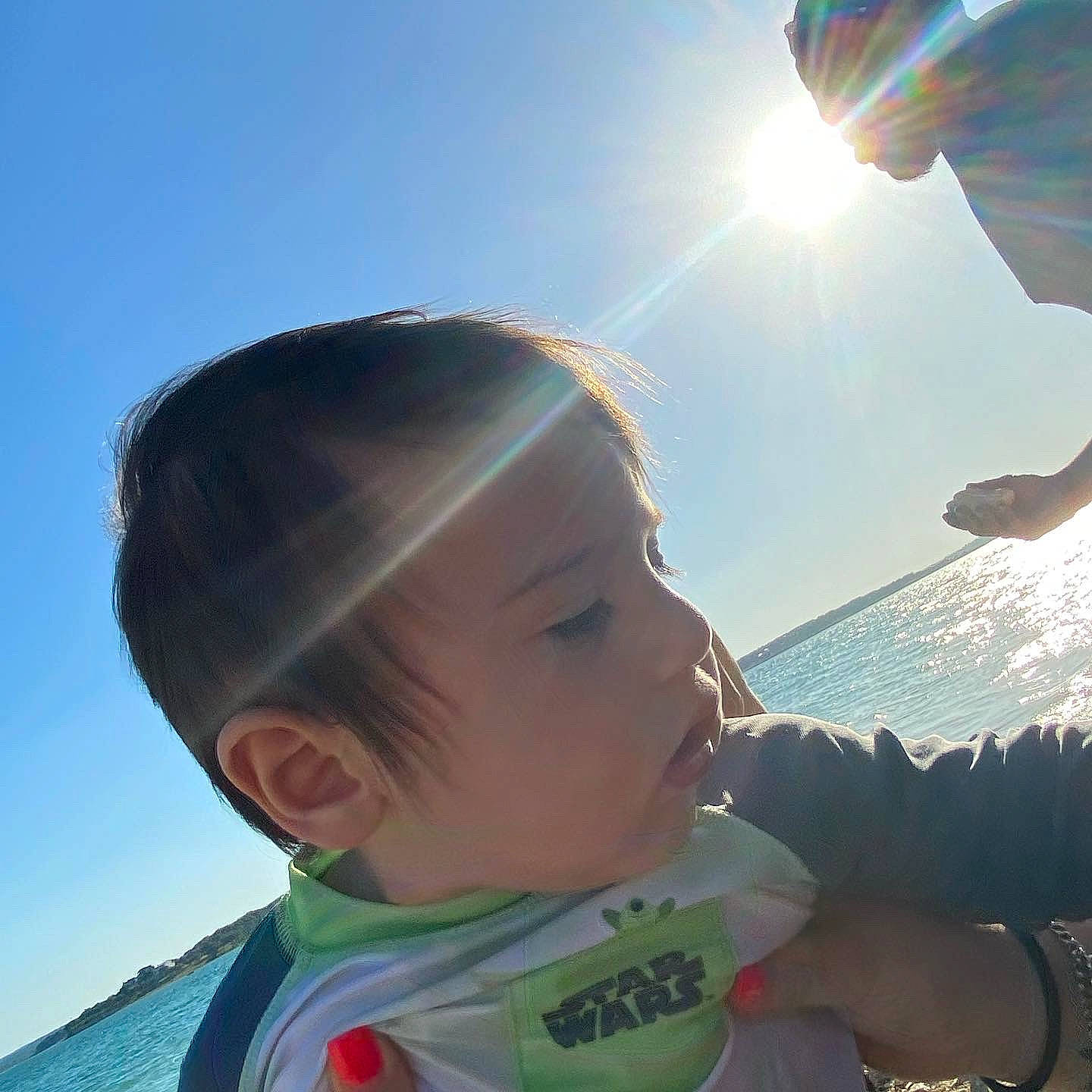 Julius is registered to the contest to win money with this photo: baby, baby_toddler_clothing, body_of_water, cloud, cool, fun, gesture, happy, human, light, mammal, people_in_nature, person, photograph, skin, sky, sunlight, travel, vertebrate, water