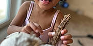Autumn is registered to the contest to win money with this photo: background_blur, child, clothing, curly_hair, cute, expression, focus, happy, holding, indoor, natural_light, person, playful, portrait, skin, smiling, toddler, twigs, window, young