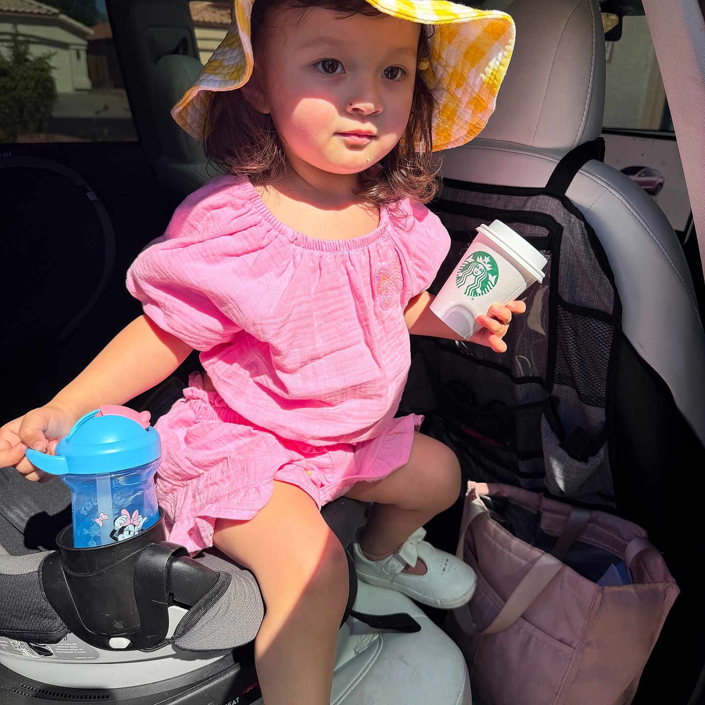 Gianna is registered to the contest to win money with this photo: child, toddler, girl, portrait, car, car_seat, sun_hat, pink_outfit, sippy_cup, coffee_cup, starbucks_cup, sneakers, sitting, indoors, vehicle, sunlight,  안전, fashion, travel, smiling