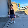 Gianna is registered to the contest to win money with this photo: child, toddler, girl, portrait, outdoor, suburban, driveway, sidewalk, house, car, suv, flags, blue_sky, sunny, dress, skirt, shoes, drink_bottle, standing, smiling
