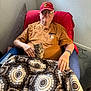 Scrim is registered to the contest to win money with this photo: elderly_man, cat, kitten, chair, blanket, glasses, cap, marine_corps_veteran, indoor, pet, hand, brown_shirt, watch, carpet, wall, comfort, companion, relaxation, casual_clothing, portrait