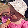 Aurora is registered to the contest to win money with this photo: toddler, child, ice_cream, cone, pink_dress, hat, bucket_hat, outdoor, sunny, summer, park, people, adult_arm, serious_face, food, snack, nature, grass, daytime, portrait