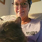 Faith joined the competition — help win amazing prizes! casual_clothing, cat, close_up, companion, couch, cozy, fluffy_cat, furniture, glasses, gray_cat, headscarf, home, indoor, person, pet, pillow, portrait, relaxed, smile, warm_lighting