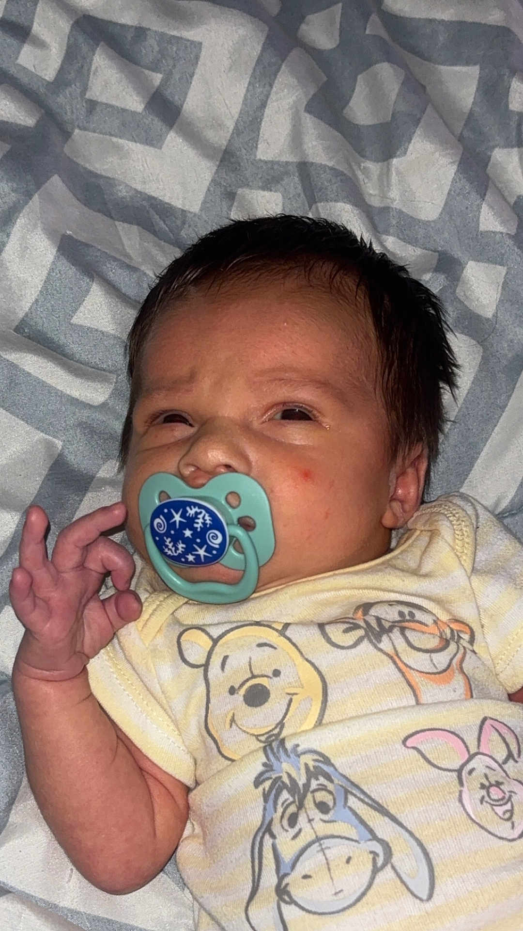 Nolan joined the competition — help win amazing prizes! baby, newborn, pacifier, onesie, winnie_the_pooh, hand_gesture, blanket, sleepwear, cute, infant, face, expression, lying_down, patterned_blanket, child, soft_lighting, indoors, portrait, person, resting