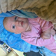 Kathalëya a rejoint le concours — aidez-le/la à gagner de superbes lots ! baby, blanket, blue_blanket, child, comfort, cozy, cute, expression, face, hands, head, home, indoors, infant, lying_down, person, pink_clothing, portrait, skin, soft_fabric