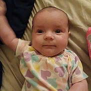 Lila joined the competition — help win amazing prizes! baby, infant, child, face, apparel, patterned_clothing, pastel_colors, heart_pattern, lying_down, bed, blanket, skin, arm, hand, cute, portrait, indoors, expression, person, young