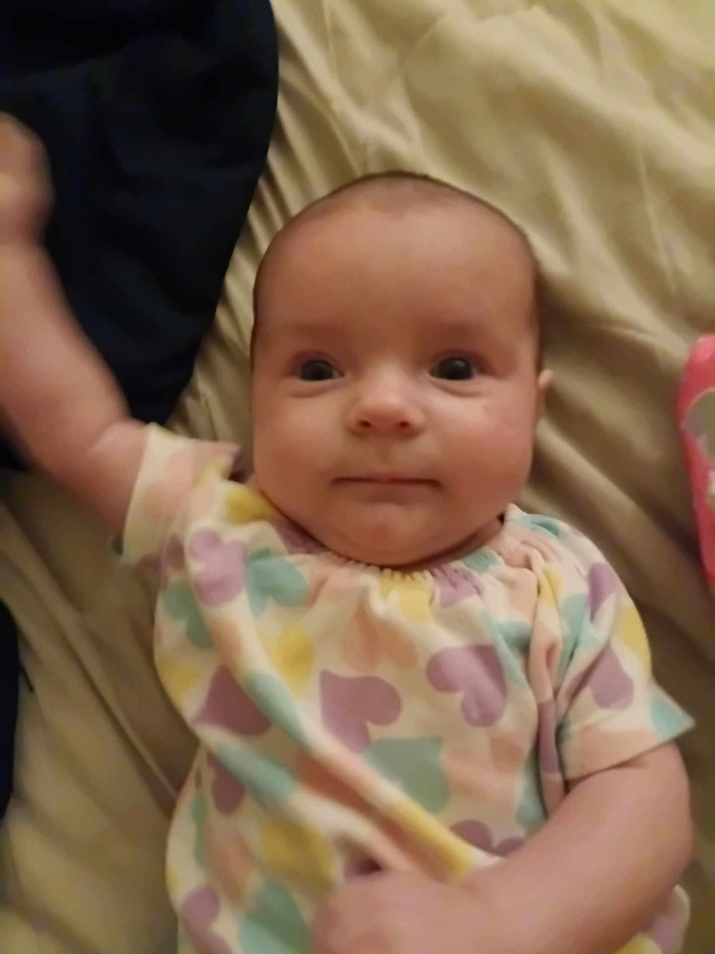 Lila joined the competition — help win amazing prizes! baby, infant, child, face, apparel, patterned_clothing, pastel_colors, heart_pattern, lying_down, bed, blanket, skin, arm, hand, cute, portrait, indoors, expression, person, young