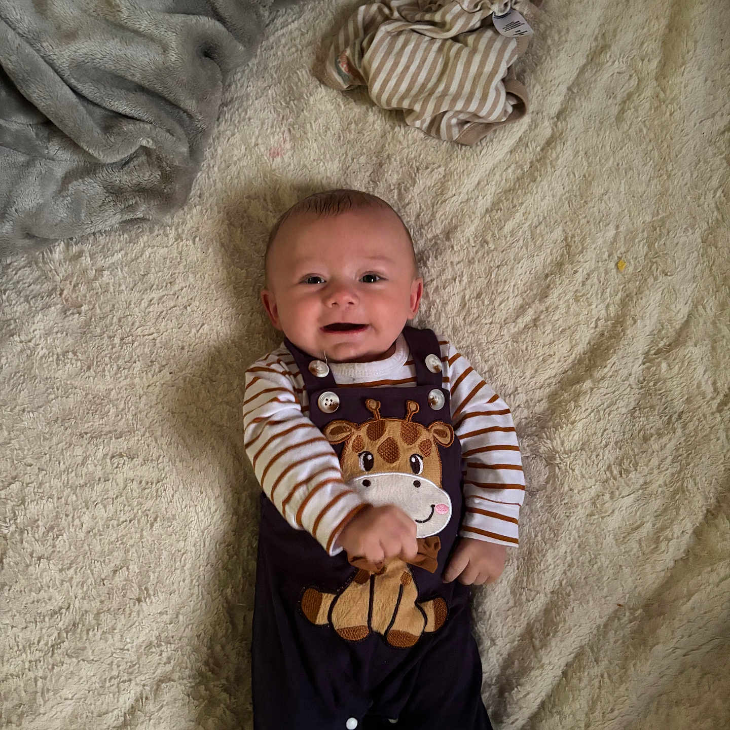 Asher joined the competition — help win amazing prizes! baby, blanket, buttoned_pants, casual, child, clothing, comfortable, cute_outfit, fabric, giraffe_design, happy, indoors, infant, lying_down, person, playful, smiling, soft_texture, striped_shirt, warm_colors