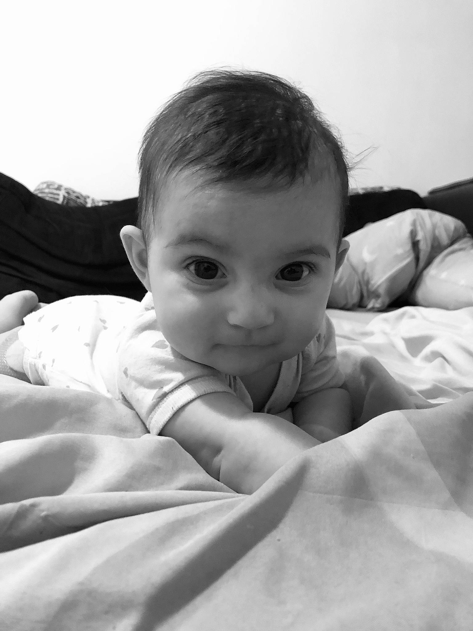 Inaya a rejoint le concours — aidez-le/la à gagner de superbes lots ! baby, bedding, child, comfort, elbow, finger, flash_photography, fur, gesture, happy, linens, monochrome, monochrome_photography, person, portrait_photography, room, sitting, sky, style, thumb