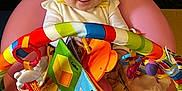 Rylie is registered to the contest to win money with this photo: baby, child, smiling, happy, indoor, toy, colorful, playmat, seat, infant, clothing, white_socks, book, soft_toys, face, person, cute, playtime, bright, cheerful