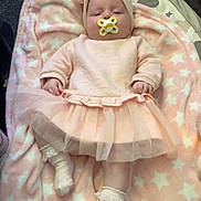 Rylie is registered to the contest to win money with this photo: baby, pacifier, blanket, pink, headband, tulle_skirt, socks, infant, cute, sleepy, soft_texture, star_pattern, lying_down, indoors, clothing, child, adorable, resting, cozy, infant_fashion