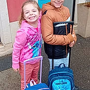 Olivia a rejoint le concours — aidez-le/la à gagner de superbes lots ! backpack, boy, building, casual_clothing, child, children, concrete, friends, girl, happy, hoodie, jackets, luggage, outdoor, pavement, plant, rainy, rolling_backpack, smiling, travel