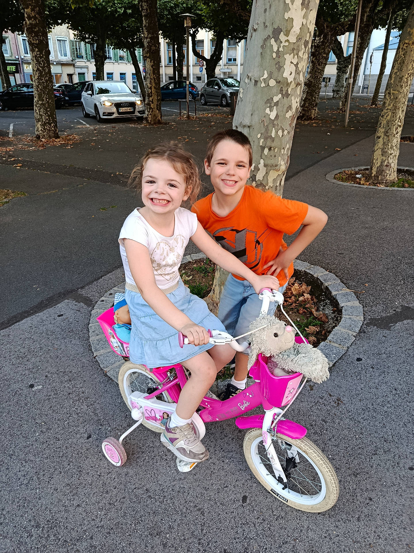 Olivia participe au concours pour gagner de l'argent avec cette photo : bicycle, boy, casual_clothing, child, children, daylight, friends, girl, happy, outdoor, parked_car, play, sidewalk, smiling, stuffed_animal, summer, toy, training_wheels, tree, urban