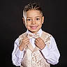Jexiel is registered to the contest to win money with this photo: bow_tie, boy, braided_hair, child, cute, dark_background, earrings, fashion, formal_wear, hands, happy, person, portrait, posing, smile, studio, style, vest, white_shirt, young