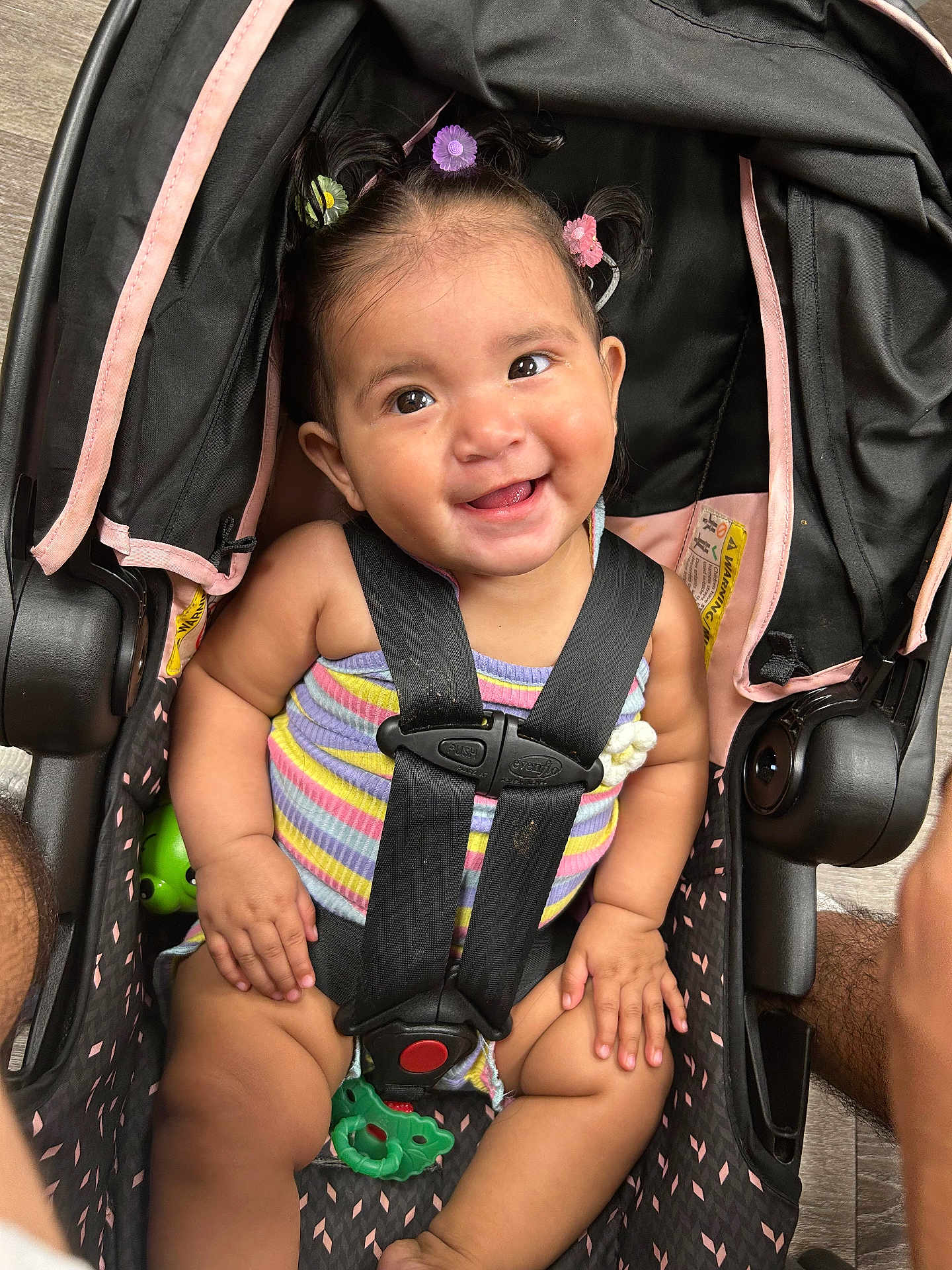 Lilah joined the competition — help win amazing prizes! baby, car_seat, smiling, child, safety_harness, hair_clips, colorful, striped_clothing, happy, cute, infant, indoors, seat, toy, person, portrait, childcare, secure, expression, closeup