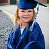child, graduation, cap, gown, smile, outdoor, portrait, young, happy, celebration, school, person, face, blue, wind, hair, tassel, pavement, building, daylight