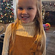 Grayleigh is registered to the contest to win money with this photo: child, girl, smiling, indoor, christmas_tree, holiday, decorations, long_hair, sweater, dress, face, portrait, home, living_room, floor, furniture, window, lights, happy, cute