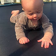 James is registered to the contest to win money with this photo: baby, infant, child, trampoline, outdoor, sunlight, onesie, crawling, hand, face, head, skin, expression, fence, tree, house, sky, shadow, playtime, daytime