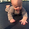 baby, infant, child, trampoline, outdoor, sunlight, onesie, crawling, hand, face, head, skin, expression, fence, tree, house, sky, shadow, playtime, daytime