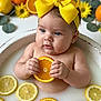 baby, child, infant, yellow_bow, headband, orange_slice, lemon_slice, milk_bath, fruit, flower, yellow_flower, water, skin, cute, portrait, sitting, hand, face, blue_eyes, earrings