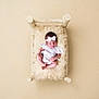 baby, newborn, sleeping, white_clothing, headband, bow, fluffy_cushion, wooden_bed, beige_background, infant, peaceful, cute, small, portrait, soft_lighting, minimalist, child, resting, cozy, indoors