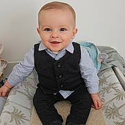 Jules participe au concours pour gagner de l'argent avec cette photo : baby, child, smiling, sitting, indoor, vest, shirt, sock, changing_table, blanket, happy, portrait, cute, infant, clothing, face, person, furniture, home, young