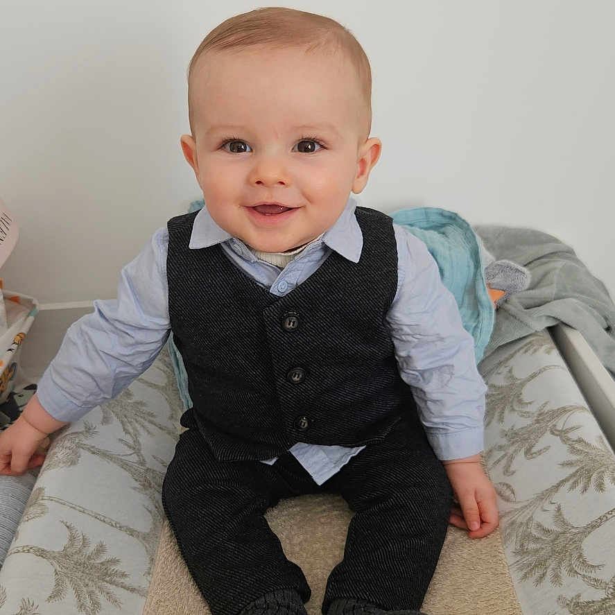 Jules participe au concours pour gagner de l'argent avec cette photo : baby, blanket, changing_table, child, clothing, cute, face, furniture, happy, home, indoor, infant, person, portrait, shirt, sitting, smiling, sock, vest, young