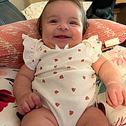 Sofia is registered to the contest to win money with this photo: baby, infant, smile, onesie, ladybug_pattern, cushion, pillow, indoor, happy, cute, child, person, furniture, floral, skin, head, arm, leg, cheerful, comfort