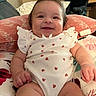baby, infant, smile, onesie, ladybug_pattern, cushion, pillow, indoor, happy, cute, child, person, furniture, floral, skin, head, arm, leg, cheerful, comfort