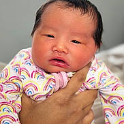 Juni Kim is registered to the contest to win money with this photo: baby, newborn, infant, child, person, hand, clothing, onesie, rainbow_pattern, sleepy, face, skin, portrait, indoor, soft_light, cute, holding, human, newborn_clothing, closeup