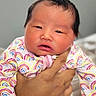 baby, newborn, infant, child, person, hand, clothing, onesie, rainbow_pattern, sleepy, face, skin, portrait, indoor, soft_light, cute, holding, human, newborn_clothing, closeup