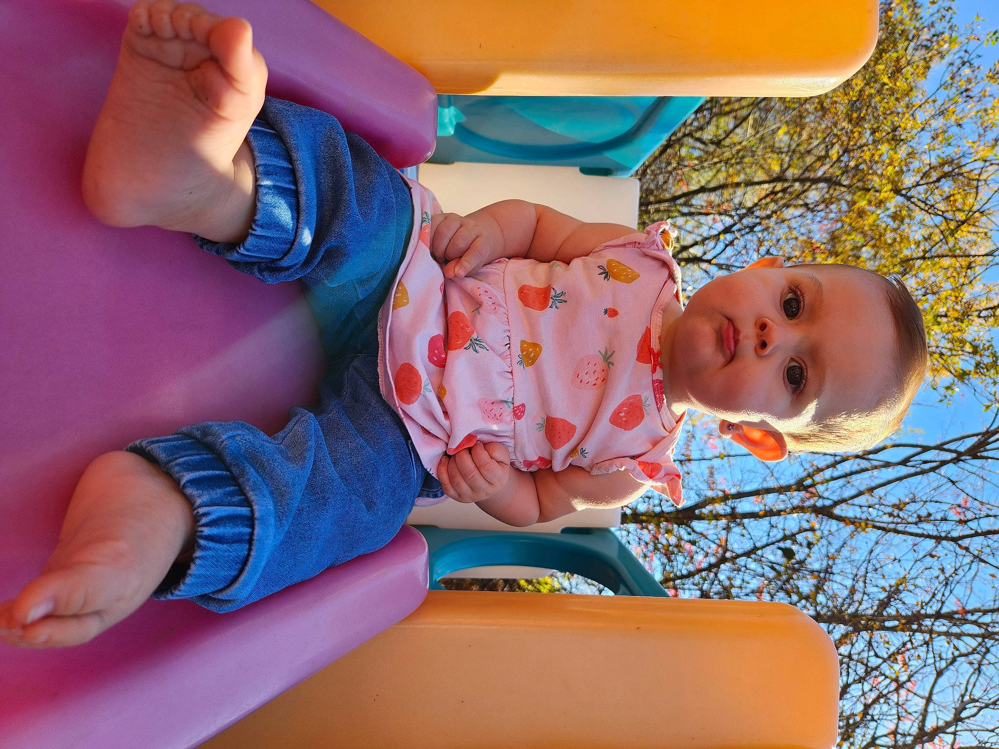 Reagan is registered to the contest to win money with this photo: azure, baby, baby_toddler_clothing, child, comfort, electric_blue, facial_expression, fun, happy, human_leg, leisure, orange, person, pink, plant, play, sitting, sky, thigh, toddler