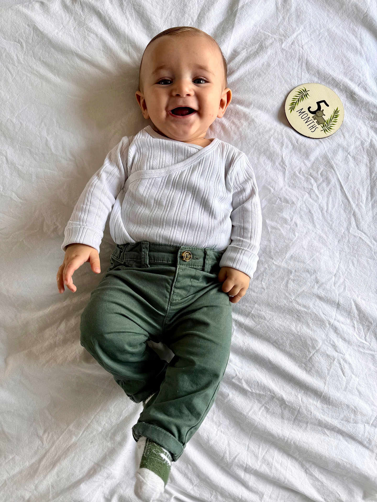 Swan a rejoint le concours — aidez-le/la à gagner de superbes lots ! baby, infant, smiling, white_clothing, green_pants, lying_down, milestone_sign, 5_months, happy, cute, child, person, white_sheet, sock, casual_wear, portrait, indoor, young_child, baby_boy, cheerful