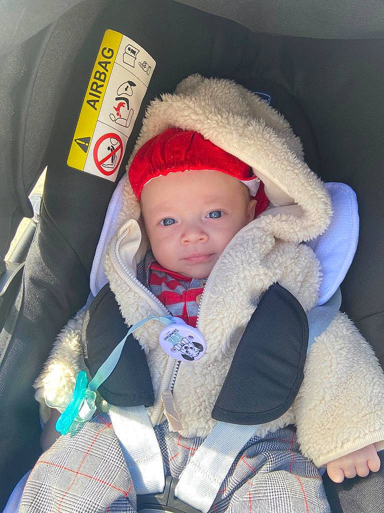 Mathias a rejoint le concours — aidez-le/la à gagner de superbes lots ! baby, baby_carriage, baby_products, baby_toddler_clothing, beanie, cap, car_seat, cheek, comfort, electric_blue, eye, head, headwear, human_body, jacket, knit_cap, person, seat_belt, skin, toddler