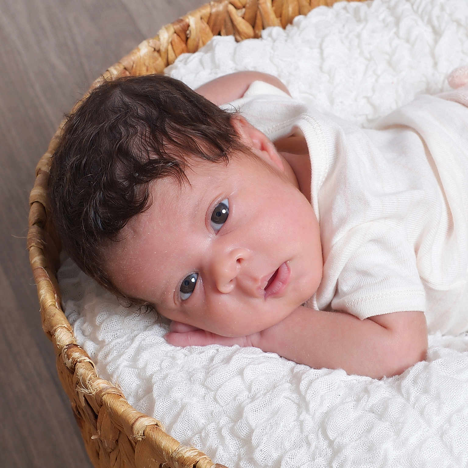Lovelyn is registered to the contest to win money with this photo: baby, infant, child, basket, blanket, white, curly_hair, lying_down, face, portrait, soft_texture, cozy, indoor, cute, newborn, expression, gaze, skin, clothing, relaxing