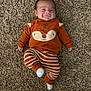 Jesse joined the competition — help win amazing prizes! baby, infant, carpet, orange_clothing, striped_pants, smile, lying_down, cute, child, face, socks, cozy, indoors, happy, playful, person, young_child, casual_wear, soft_texture, comfortable
