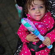 Stella joined the competition — help win amazing prizes! toddler, child, stroller, pink_raincoat, polka_dots, toy, glowing_toy, curly_hair, blue_eyes, outdoor, seatbelt, happy, cute, portrait, hands, face, smile, baby, clothing, playful