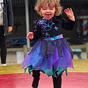 Stella is registered to the contest to win money with this photo: toddler, child, girl, curly_hair, purple_dress, blue_dress, spider_web, outdoor, playful, jumping, smiling, happy, person, fashion, costume, leggings, fun, movement, joy, blurred_background